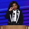 Jasmine Crockett, in a black-and-white suit, wipes away a tear while addressing the DNC convention.