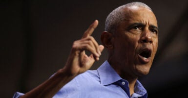 Barack Obama in a blue shirt pointing with his mouth open.