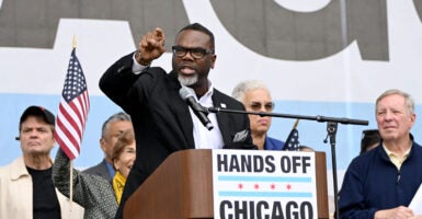 Chicago Mayor Brandon Johnson at a podium pointing while speaking. Podium reads: "Hands Off Chicago."