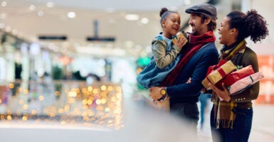 Mixed race couple with adorable child go Christmas shopping in a mall.