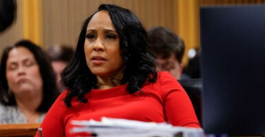 Fani Willis in a red outfit sits in a courtroom.