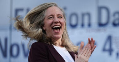 Abigail Spanberger laughs and claps. The Associated Press predicts she will win the Virginia governor's race