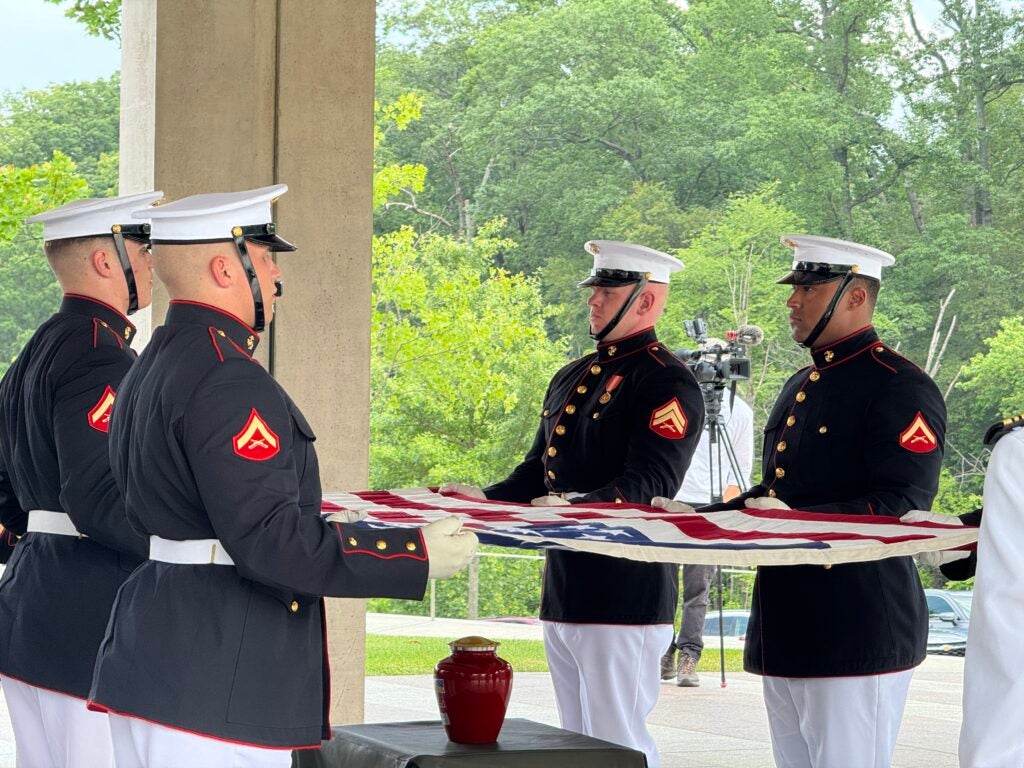 Marines hold American flag over urn of Thomas Harris. 
