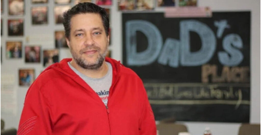 Pastor Chris Avell stands in front of a "Dad's Place" sign.