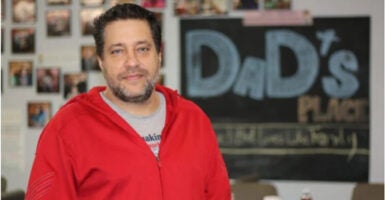 Pastor Chris Avell stands in front of a "Dad's Place" sign.