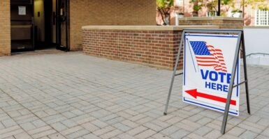 A "Vote Here" directional sign sits outside of polling place.