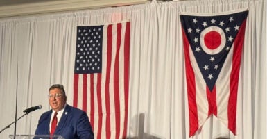 Ohio GOP Chairman Alex Triantafilou stands at a podium with the American and Ohio flags behind him.