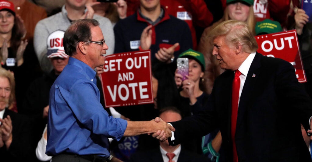 President Donald Trump shakes hands with Mike Braun during a campaign rall.