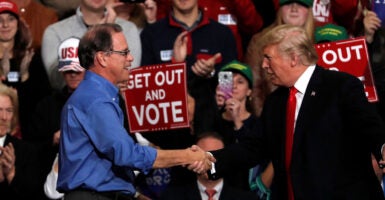 President Donald Trump shakes hands with Mike Braun during a campaign rall.