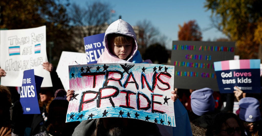 Child holding a sign that says "trans pride" at the Supreme Court.