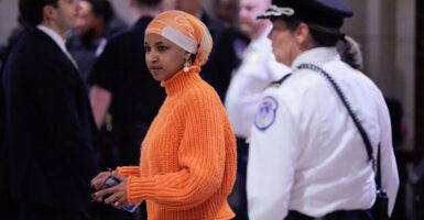 Ilmar Omar stands in a hallway with a cell phone in her left hand.