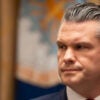 Pete Hegseth turns his head to his right during a meeting.