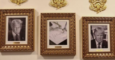 A portrait of the Joe Biden autopen flanked by portraits of Donald Trump.