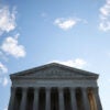 Top half of the U.S. Supreme Court building against a blue sky with a few scattered clouds.