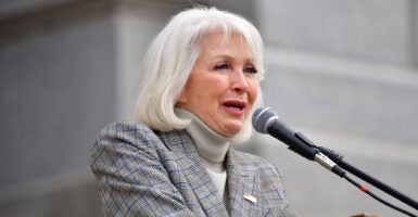 Tina Peters in a gray suit speaks during a rally.