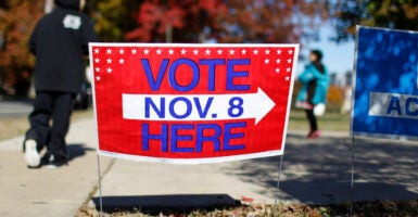 People walk past a vote-here sign advertising the Virginia Senate elections taking place on November 8, in Alexandria, Virginia, November 5, 2011. Virginia's state Senate elections next week are shaping up as an early signal for President Barack Obama ahead of national elections next year. REUTERS/Molly Riley (UNITED STATES - Tags: POLITICS ELECTIONS)