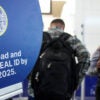 TSA agent checks out a passenger next to a sign advertising Real ID.