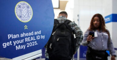 TSA agent checks out a passenger next to a sign advertising Real ID.