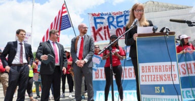 Rally in front of Supreme Court in favor of Birthright Citizenship. In background is upside down American flag and banner reading 