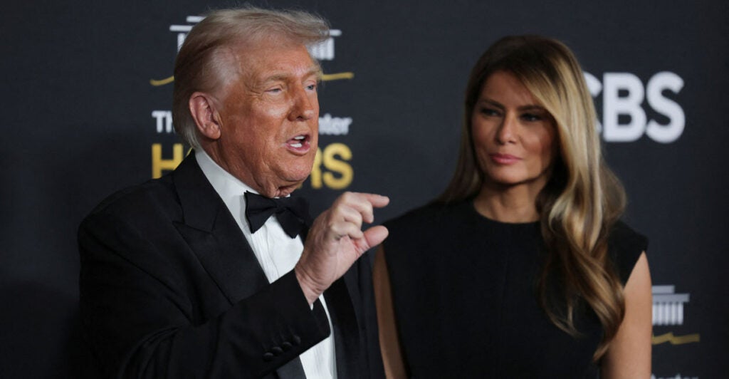 Donald and Melania Trump on red carpet for Kennedy Center Honors. Trump in a tux and Melania in a black gown.