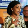 Ilhan Omar speaking at political event, hand on her chest.