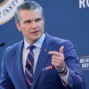 Pete Hegseth speaks while in a blue suit and blue, white and red tie.