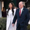Kristi Noem in a white outfit and Tom Holman in a dark suit walk outside the White House.