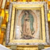 The original tilma depicting Mary, mother of Jesus, hangs against a gold backdrop at Guadelupe Basilica.
