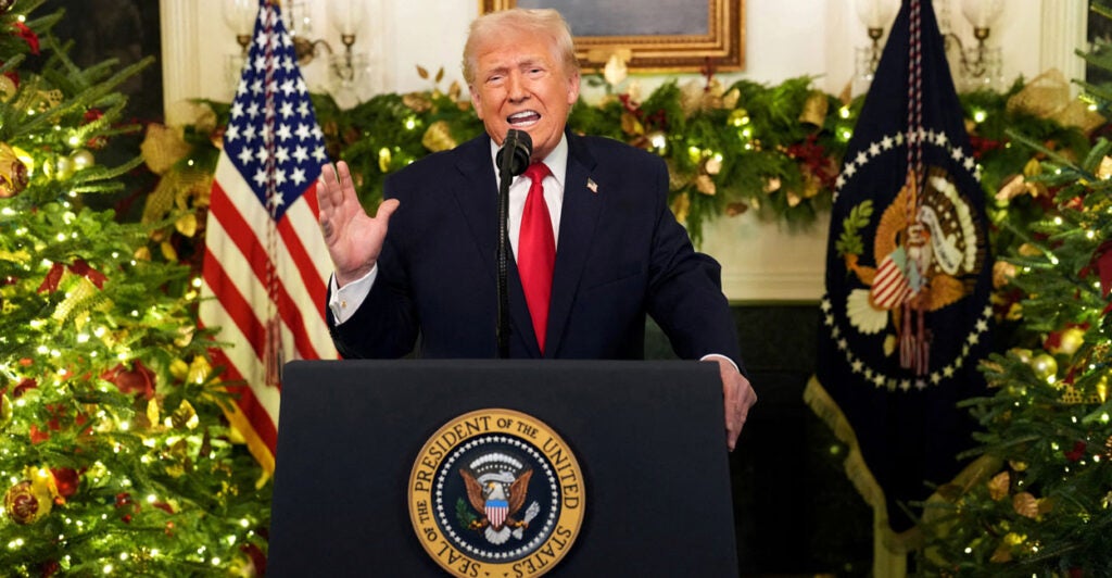 Donald Trump addresses the nation in front of a garland-covered fireplace.