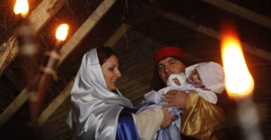 A couple plays Mary and Joseph with the male holding an infant.