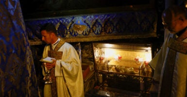 A priest stands near the figure of the baby Jesus at the Grotto in Bethlehem.