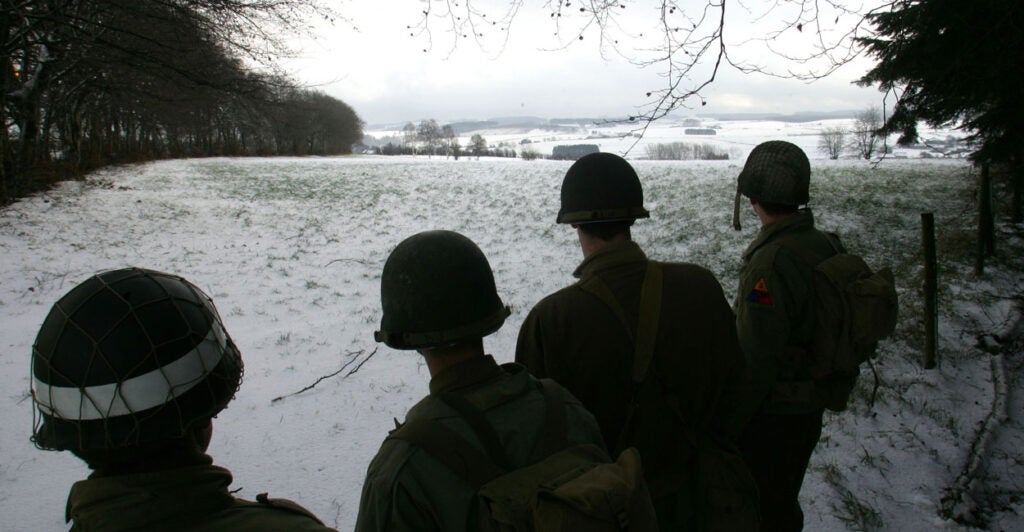 Black-and-white photo of U.S. soldiers overlooking site of Battle of the Bulge.