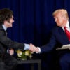 President Donald Trump shakes hands with Argentina's President Javier Milei as they sit in front of a blue curtain.