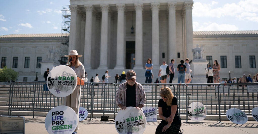 Pro-life activists kneel and stand outside the U.S. Supreme Court.
