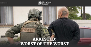 An officer leads away a criminal illegal alien in handcuffs.