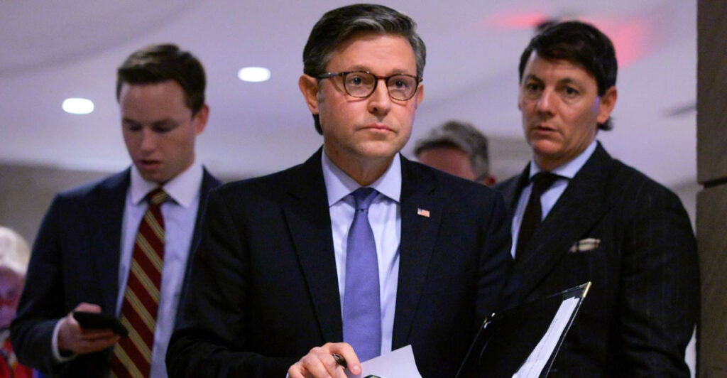 Speaker of the House Mike Johnson walks down a capitol hallway.