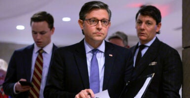 Speaker of the House Mike Johnson walks down a capitol hallway.