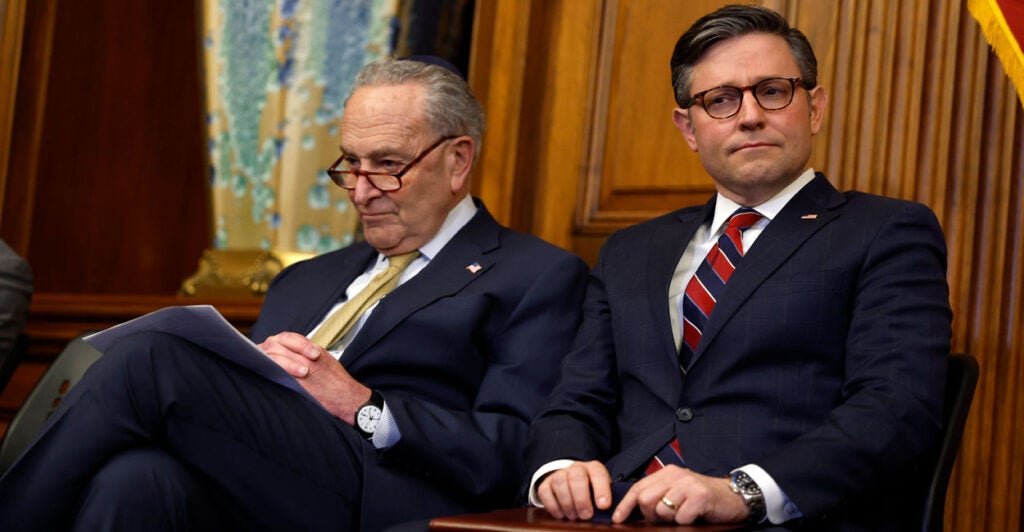Senate Minority Leader Chuck Schumer and Speaker of the House Mike Johnson sit together at a Hannukah celebration in the Capitol.
