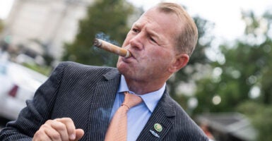 Congressman Troy Nehls smokes a cigar in front of the capitol.