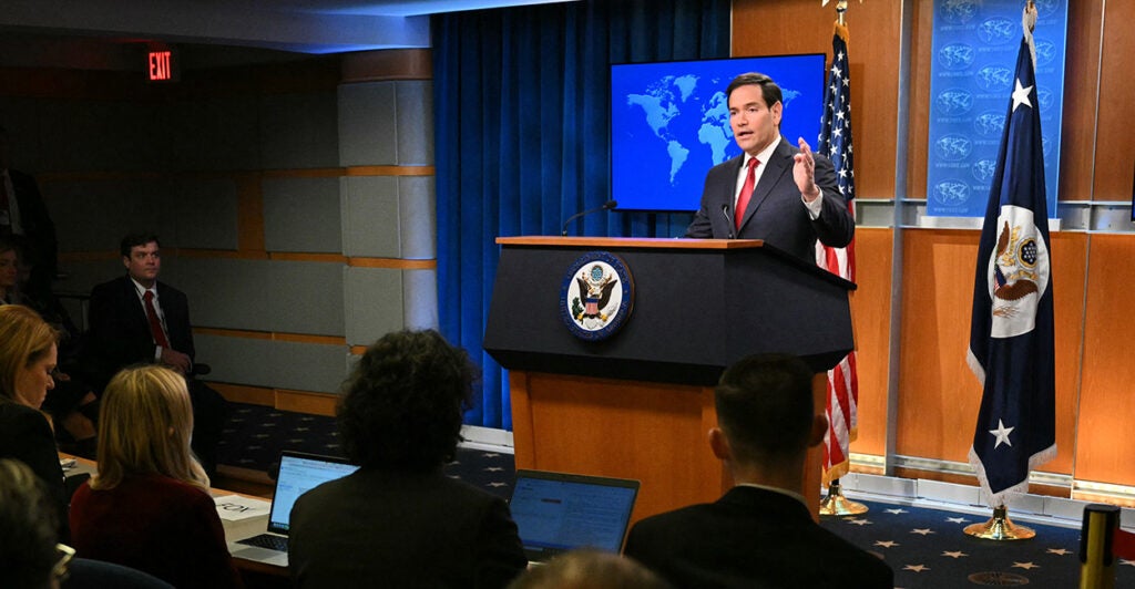 Marco Rubio behind a podium speaks to reporters.