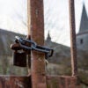 A chain lock on a rusted iron gate, with church in the background.