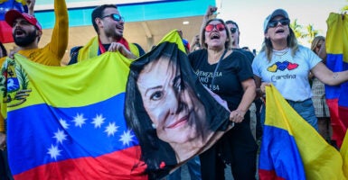 Venezuelans in Florida cheer and wave a flag with the face of opposition leader Maria Corina Machado.