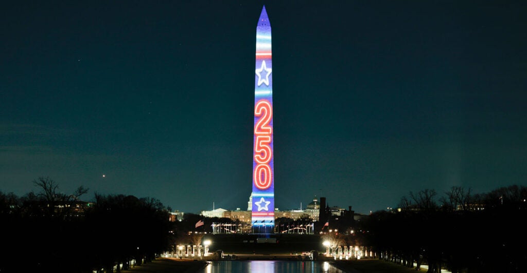 Washington Monument lit up with the projection of "250" in red against a blue background.