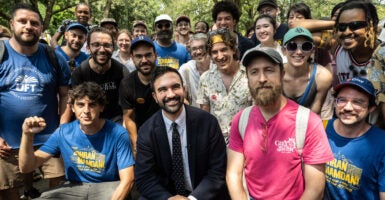 Then-candidate Zohran Mamdani surrounded by supporters in a park.