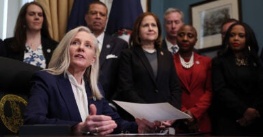 Virginia Gov. Abigail Spanberger at a desk, holding a document, as several people look on.