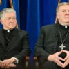Cardinal Blase Joseph Cupich and Cardinal Joseph Tobin sit together in front of a blue curtain.