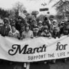 Black-and-white photo of a group of marchers behind sign reading "March for Life: Support the life principles."