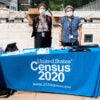 Two female masked 2020 Census workers stand behind a table outside Lincoln Center