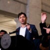 Minneapolis Mayor Jaco Frey speaks at a podium as an sign-language interpreter raises one hand and uses his left hand to point at Frey.