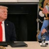 Donald Trump listens to DHS Secretary Kristi Noem as they sit at a table.